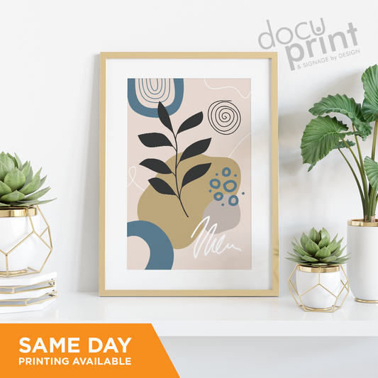 A3 promotional poster featuring a leaf design, framed and displayed on a shelf next to small plants, custom designed and printed by Docuprint in Fremantle, Perth, Australia