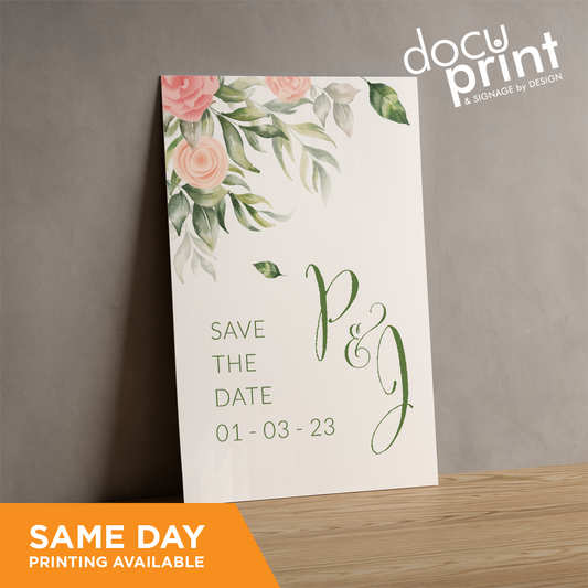 A standing A5 size card with floral design and text 'SAVE THE DATE' printed on it, placed against a wall, custom designed and printed by Docuprint in Fremantle, Perth, Australia