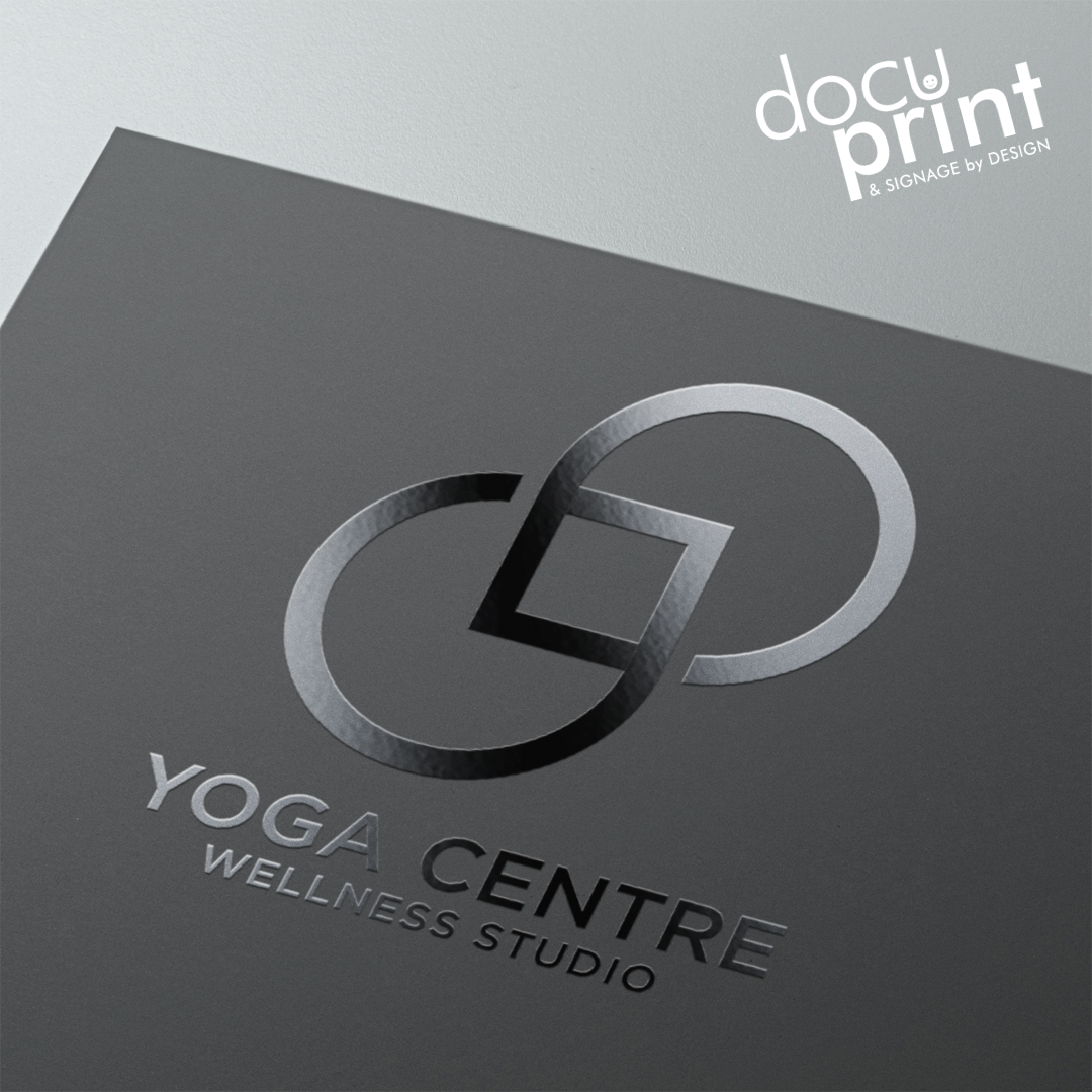 A business card with a flat spot UV effect on a Yoga Wellness Centre studio logo, presented on a grey background with a printed logo and text that reads 'Yoga Wellness Centre Studio', custom designed and printed by Docuprint in Fremantle, Perth, Australia