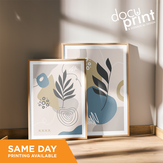 Two framed posters with abstract designs displayed on a wooden floor, with natural lighting and shadows, custom designed and printed by Docuprint in Fremantle, Perth, Australia