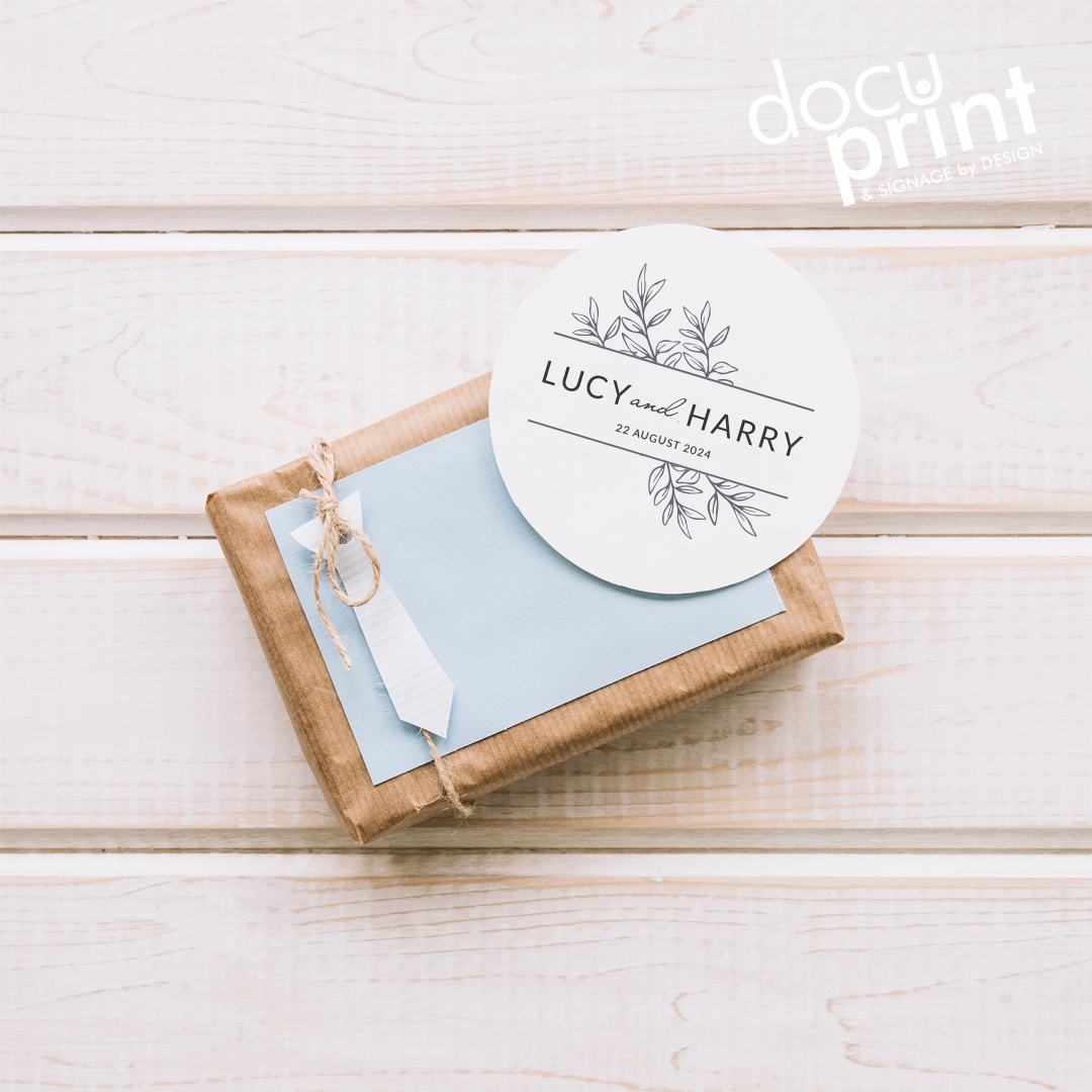 A present with a round card on top, that has a white background and a printed name and address on it, custom designed and printed by Docuprint in Fremantle, Perth, Australia