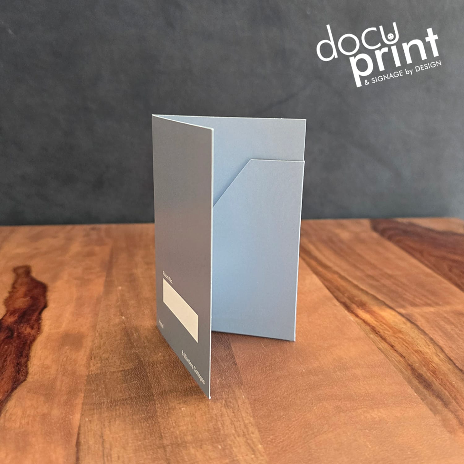 grey hotel key card holders spread out on a wooden table. Custom made, designed and printed by Docuprint Fremantle in WA.