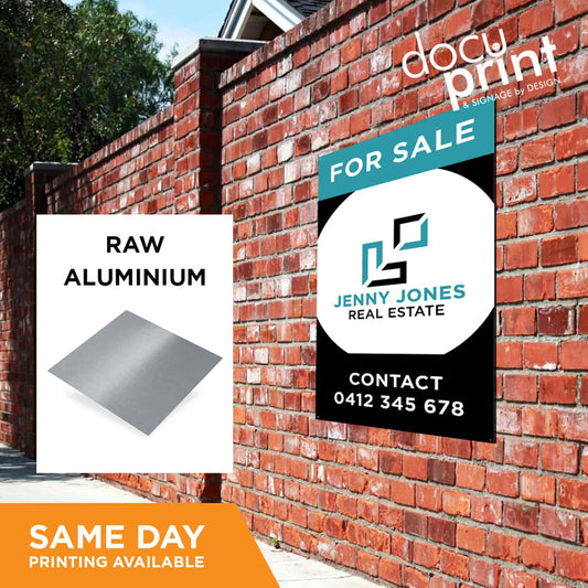 A 'For Sale' sign featuring a raw aluminium finish, placed against a red brick wall. The sign shows the brand logo of Jenny Jones Real Estate, custom designed and printed by Docuprint in Fremantle, Perth, Australia. 