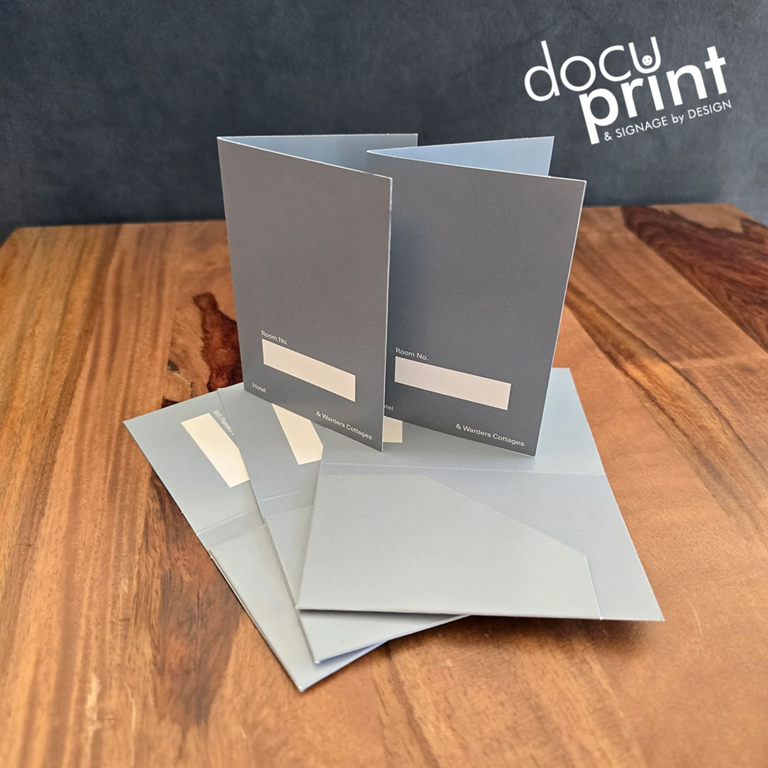 grey hotel key card holders spread out on a wooden table. Custom made, designed and printed by Docuprint Fremantle in WA. 