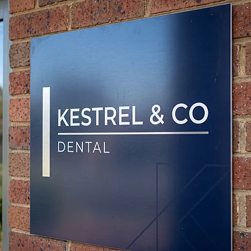 Navy aluminium composite business sign mounted on a brick shopfront wall