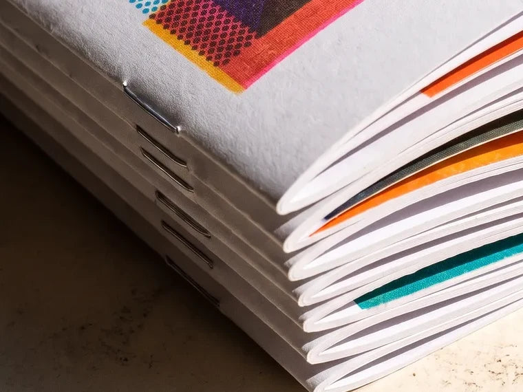 Close-up of stitched spines on a stack of booklets