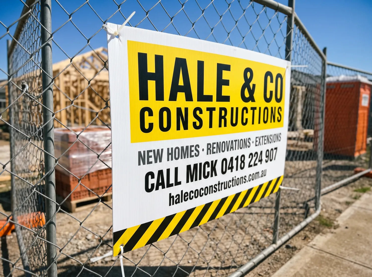 Corflute builder sign cable-tied to a construction site fence