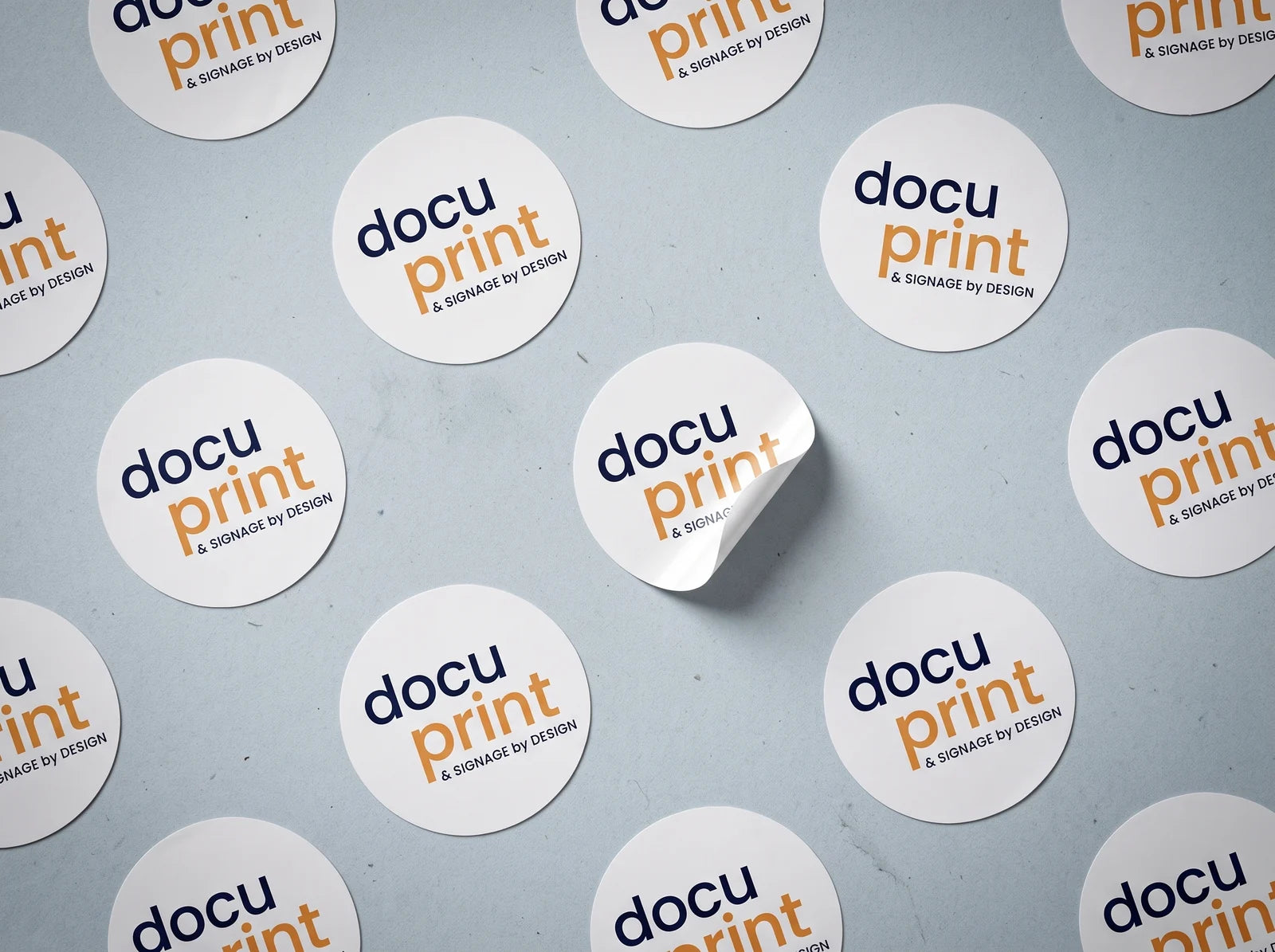 Round branded logo stickers laid out in a grid with one peeling up